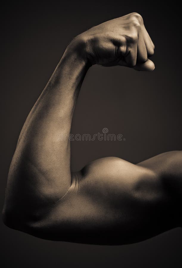 A young African American man flexing his biceps, studio shot. A young African American man flexing his biceps, studio shot.