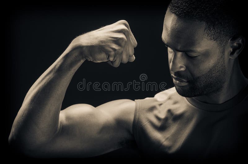 A young African American man flexing his biceps, studio shot. A young African American man flexing his biceps, studio shot.