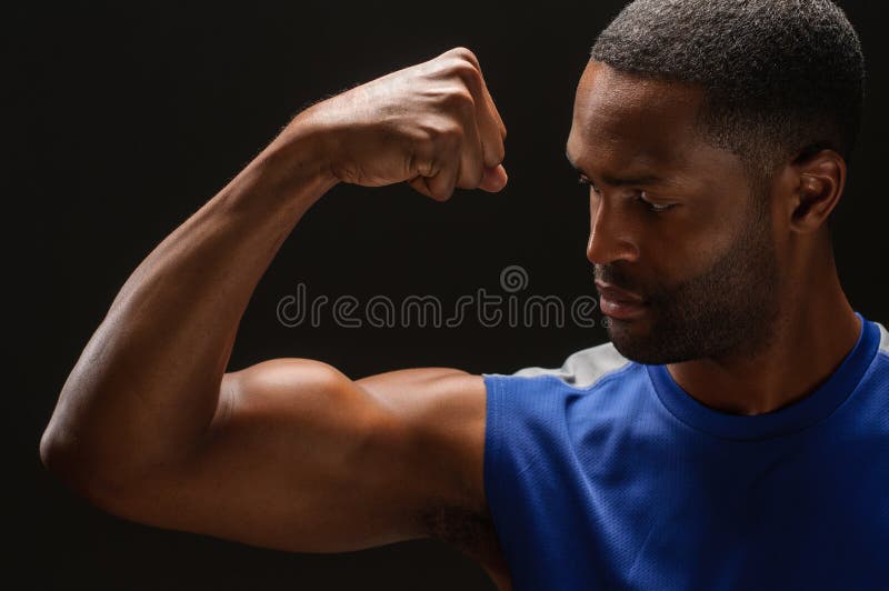 A young African American man flexing his biceps, studio shot. A young African American man flexing his biceps, studio shot.