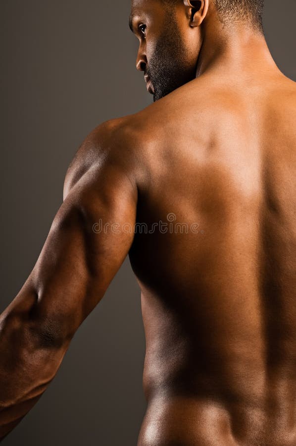A young African American man flexing his triceps, studio shot. A young African American man flexing his triceps, studio shot.