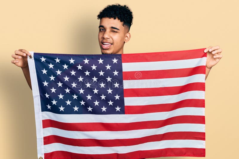Young African American Man Holding United States Flag Winking Looking ...