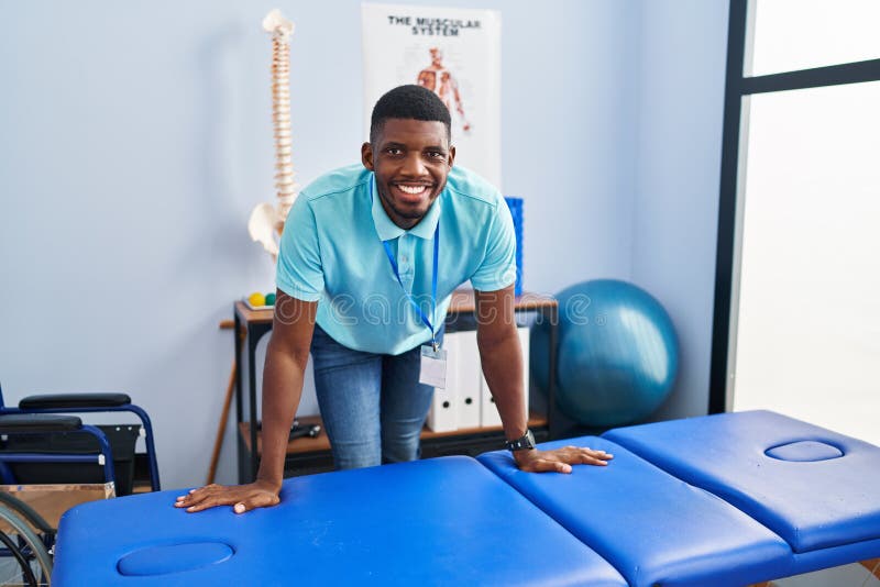 Young african american man physiotherapist smiling confident standing al rehab clinic stock photos