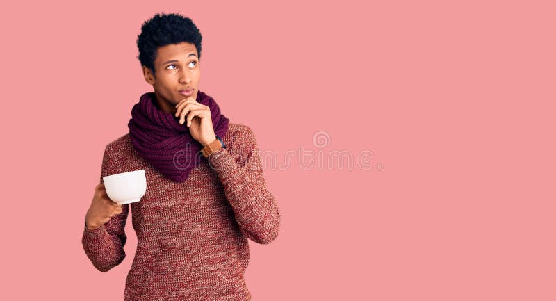 Young african american man wearing winter scarf and drinking a cup of hot coffee serious face thinking about question with hand on stock image