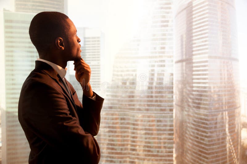 Young african-american thoughtful businessman looking through wi
