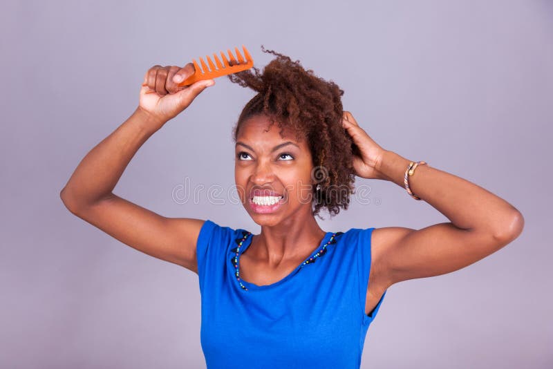 Young African American woman combing her frizzy afro hair - Blac royalty free stock image Young African American woman combing her frizzy afro hair - Blac royalty free stock image