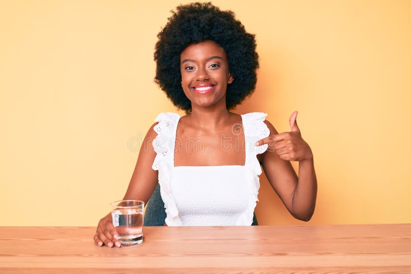 Young african american woman drinking glass of water pointing finger to one self smiling happy and proud