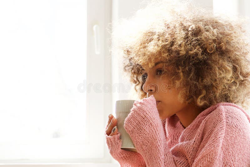 Young african american woman drinking hot cup of coffee in the morning