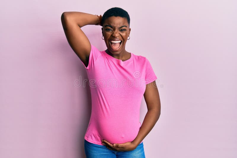 Young african american woman expecting a baby, touching pregnant belly crazy and scared with hands on head, afraid and surprised