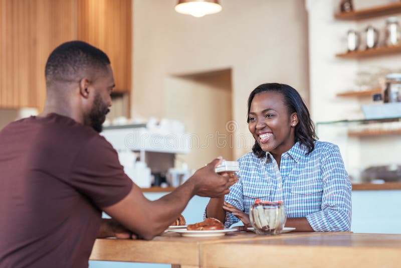 Young African man giving a present to his smiling girlfriend royalty free stock image Young African man giving a present to his smiling girlfriend royalty free stock image