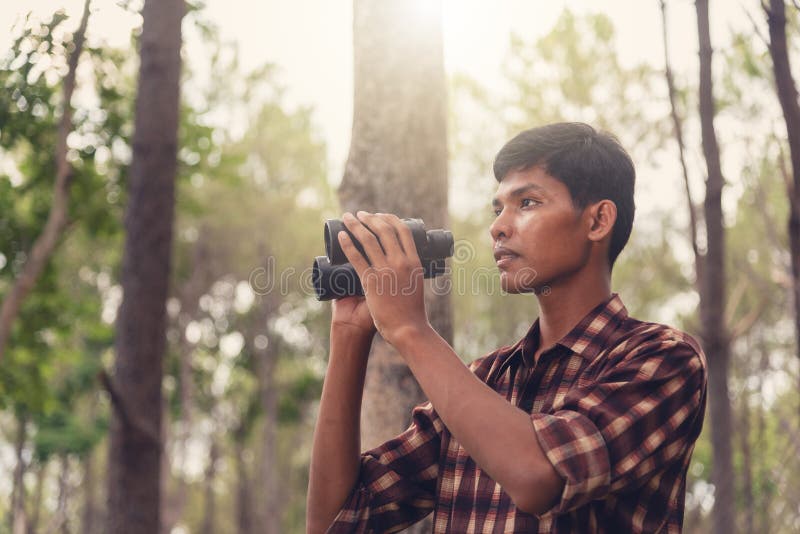 Young African man looking through binocular in the forest, Travel concept. stock photo