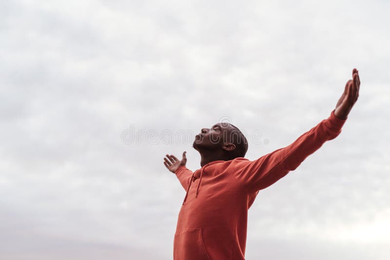 Young African man standing alone outside embracing nature