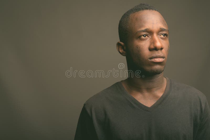 Young African man wearing black shirt against gray background stock images Young African man wearing black shirt against gray background stock images