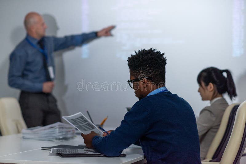 Young African programmer working with papers at seminar stock image