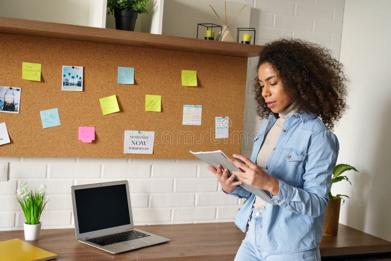 Young african teen girl study work from home office thinking hold notebook.