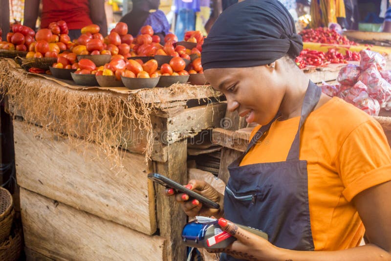 African Woman Selling in a Local African Market Holding a Mobile Point