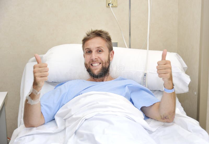 Joven Americano hombre acostada en una cama sobre el enfermo o enfermo pero dar pulgar arriba feliz a positivo lucha contra enfermedad energía.