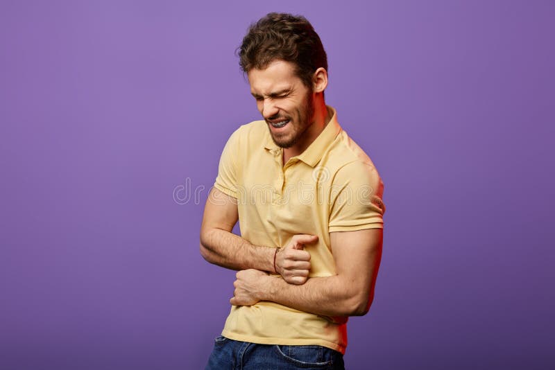 Young angry handsome man suffering from pain in his stomach royalty free stock images Young angry handsome man suffering from pain in his stomach royalty free stock images