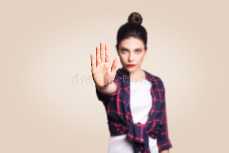Young annoyed woman with bad attitude making stop gesture with her palm outward, saying no, expressing denial or restriction.