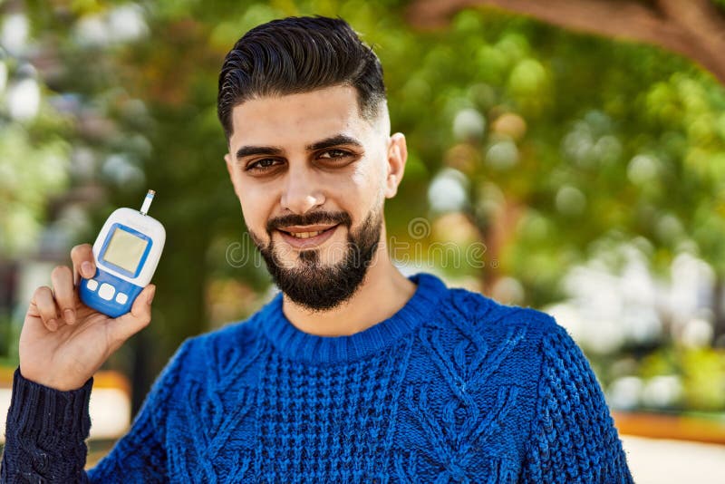 Young arab man smiling confident holding glucometer at park stock images