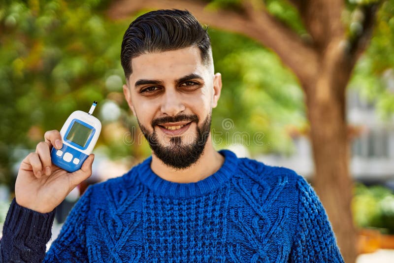Young arab man smiling confident holding glucometer at park stock photography