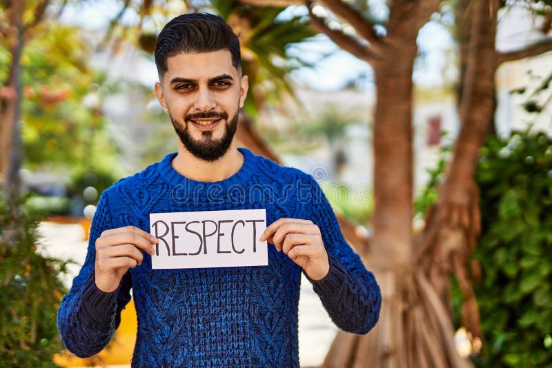 Young arab man smiling confident holding respect banner at park royalty free stock image