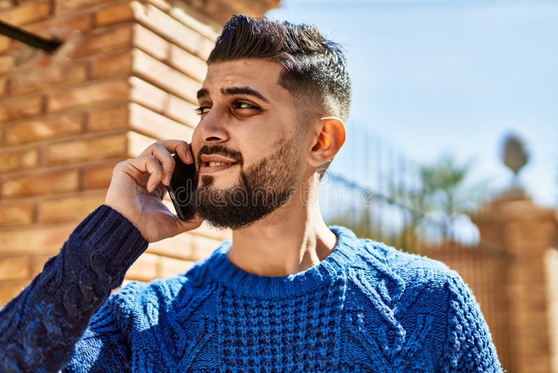 Young arab man smiling confident talking on the smartphone at street stock images