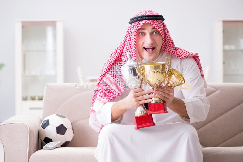 The young arab man watching football sitting on sofa