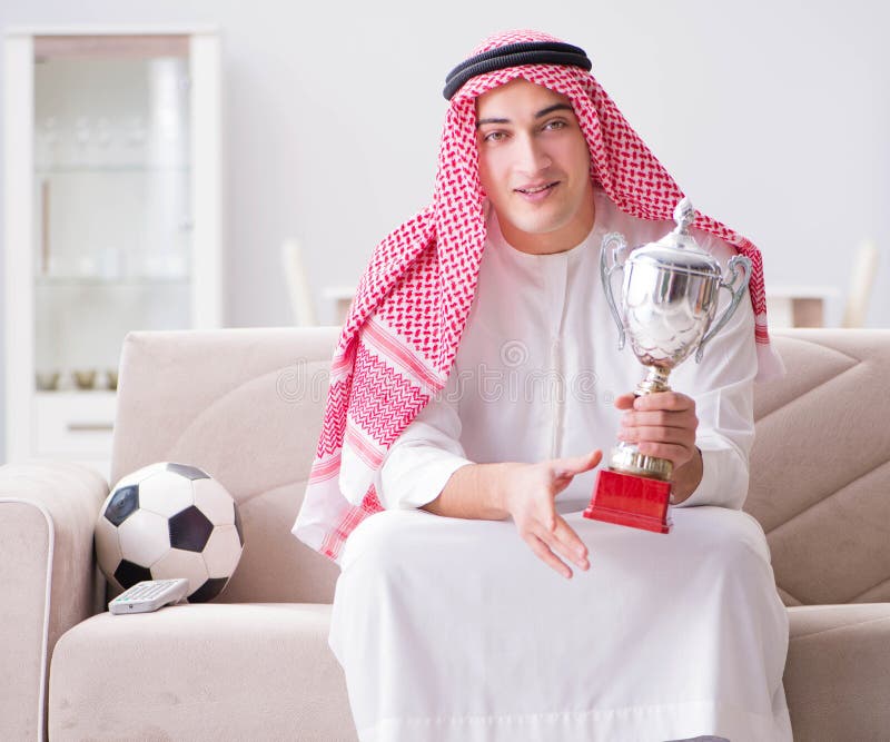 Young arab man watching football sitting on sofa stock image Young arab man watching football sitting on sofa stock image