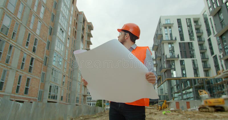 Young Architect or Builder with Hard Hat Holding Blueprint in His Hands ...