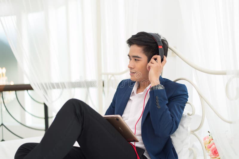 Young Asia man relaxing on the bed, listening to music with head royalty free stock image Young Asia man relaxing on the bed, listening to music with head royalty free stock image