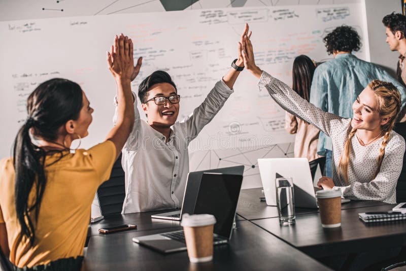 young asian businessman taking high fives to female colleagues at modern stock photos young asian businessman taking high fives to female colleagues at modern stock photos