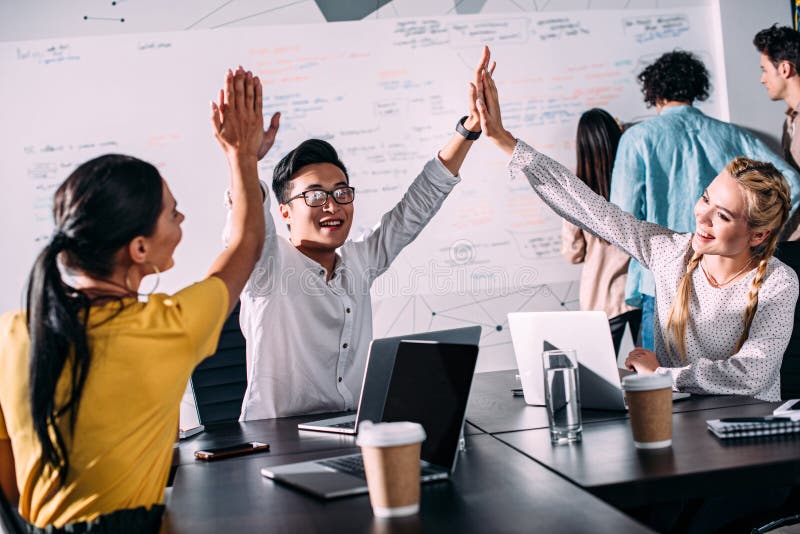young asian businessman taking high fives to female colleagues at modern stock image young asian businessman taking high fives to female colleagues at modern stock image