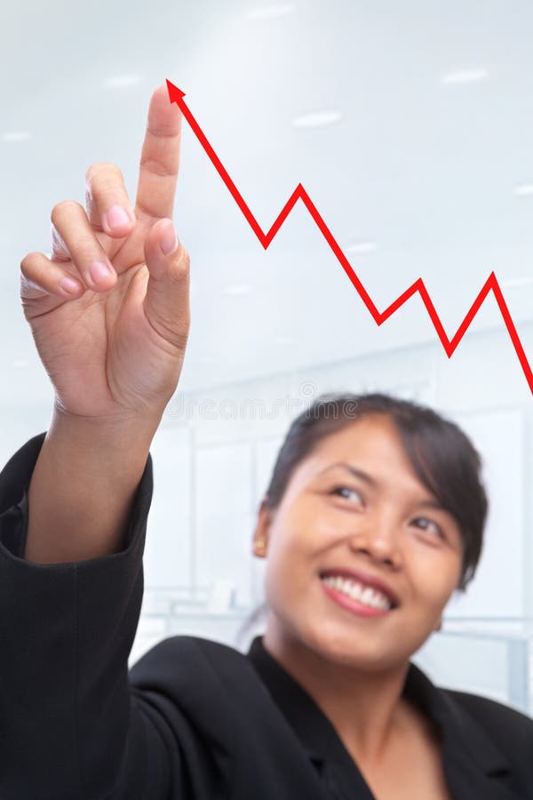 Young Asian businesswoman pointing her index finger to growth graphic in see through screen in office. PS : focus on index finger. Young Asian businesswoman pointing her index finger to growth graphic in see through screen in office. PS : focus on index finger