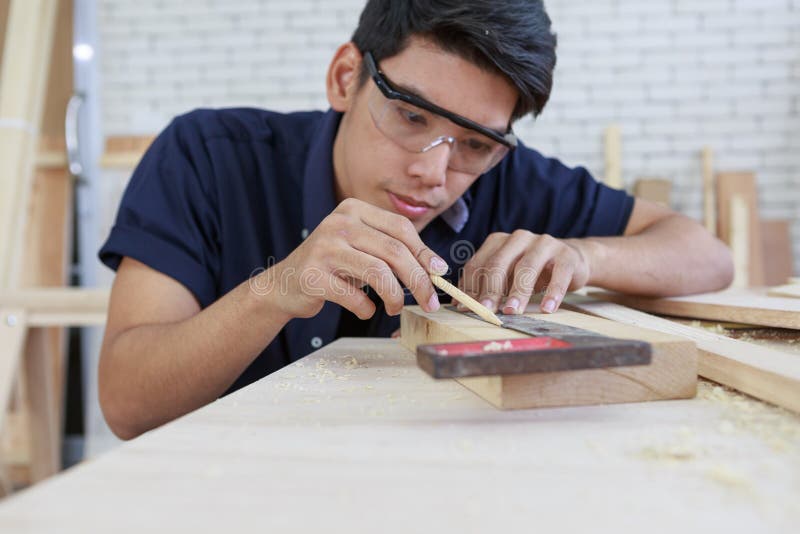 Young asian carpenter measuring on wooden job with try square