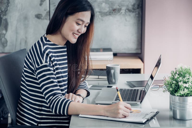 Young asian casual businesswoman writing report on office desk,work at home with online e-commerce job concept.