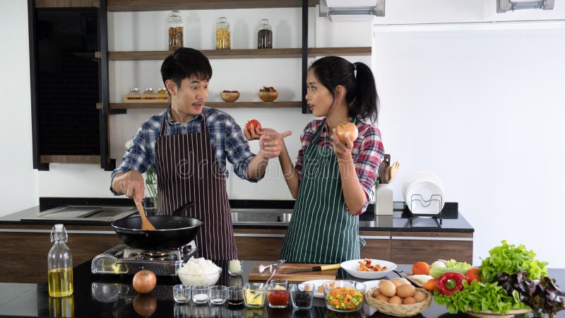 Young Asian couple are happy to cook together, two families are helping each other prepare to cook in the kitchen royalty free stock image Young Asian couple are happy to cook together, two families are helping each other prepare to cook in the kitchen royalty free stock image