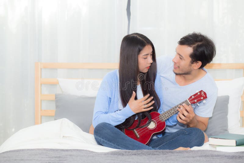 Young Asian couple playing ukulele relaxing with happiness and joyful in bedroom. stock photo Young Asian couple playing ukulele relaxing with happiness and joyful in bedroom. stock photo