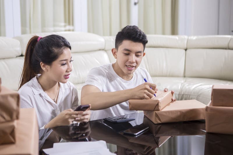 Asian couple writing the address on a package royalty free stock photography Asian couple writing the address on a package royalty free stock photography