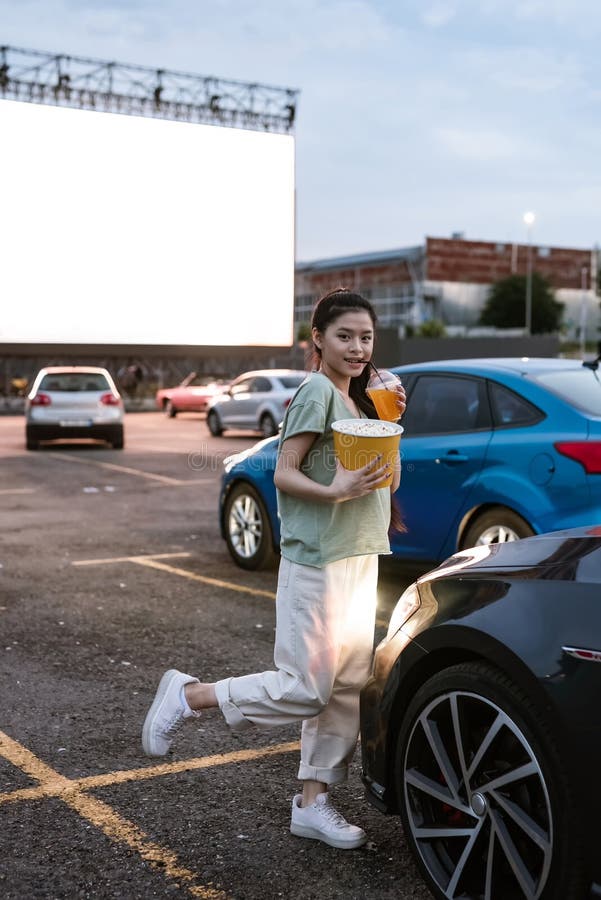 Young asian girl standing on car parking at auto cinema