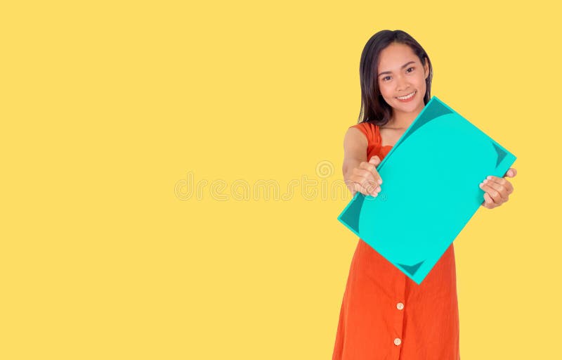 Young Asian girl in orange dress shows a big green book to the camera yellow background royalty free stock photography Young Asian girl in orange dress shows a big green book to the camera yellow background royalty free stock photography