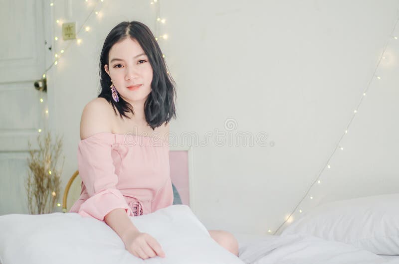 Young Asian Girl with pillow sitting in bed and smiling to camera at home in the morning royalty free stock image Young Asian Girl with pillow sitting in bed and smiling to camera at home in the morning royalty free stock image