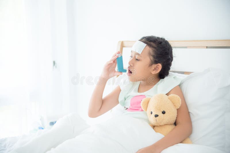 Girl sitting on bed and using broncodilator inhaler stock photography