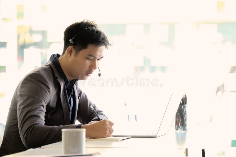 Young asian handsome male customer support phone operator with headset working in call center royalty free stock photography Young asian handsome male customer support phone operator with headset working in call center royalty free stock photography