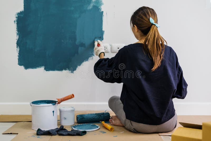 Young asian happy woman painting interior wall with paint roller stock images Young asian happy woman painting interior wall with paint roller stock images