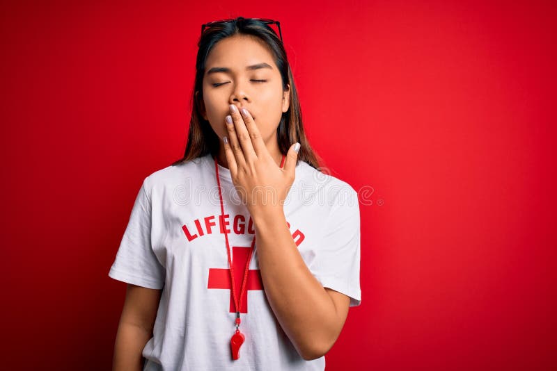 Young asian lifeguard girl wearing t-shirt with red cross using whistle over isolated background bored yawning tired covering royalty free stock image