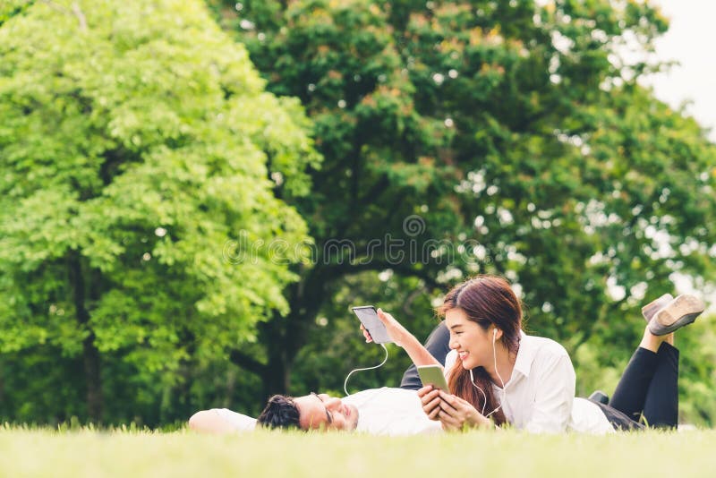 Young Asian lovely couple or college students listening to music together in the garden, with copy space royalty free stock images Young Asian lovely couple or college students listening to music together in the garden, with copy space royalty free stock images