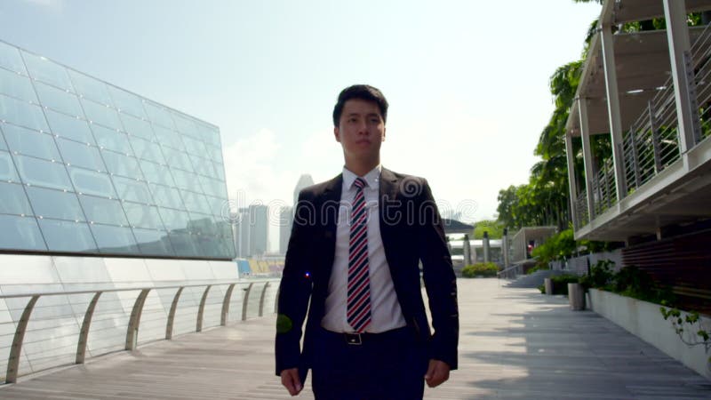 Young asian man in business suit walking confidently outdoor in slow motion