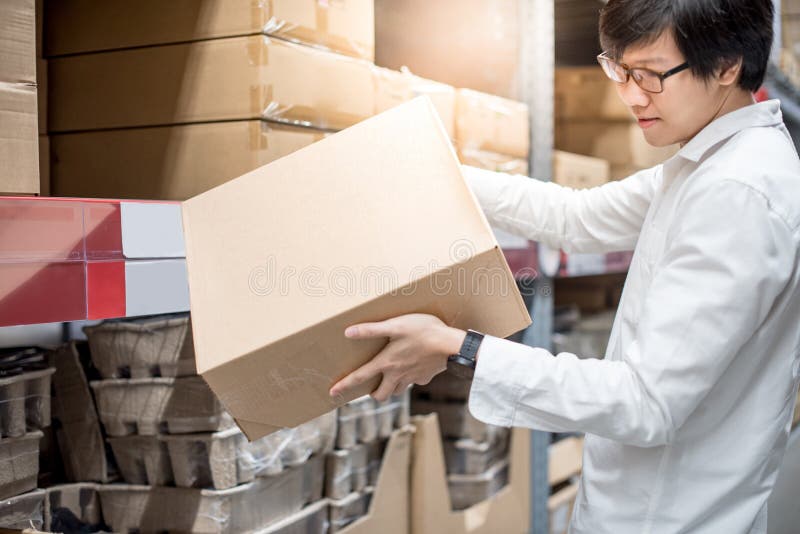 Young Asian man carrying paper boxes in warehouse stock photo Young Asian man carrying paper boxes in warehouse stock photo