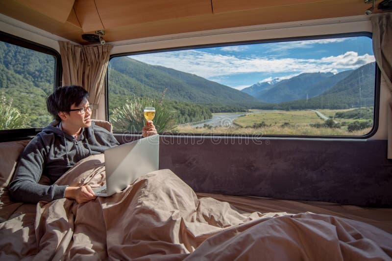 Young Asian man drinking beer and working with laptop in camper stock images Young Asian man drinking beer and working with laptop in camper stock images