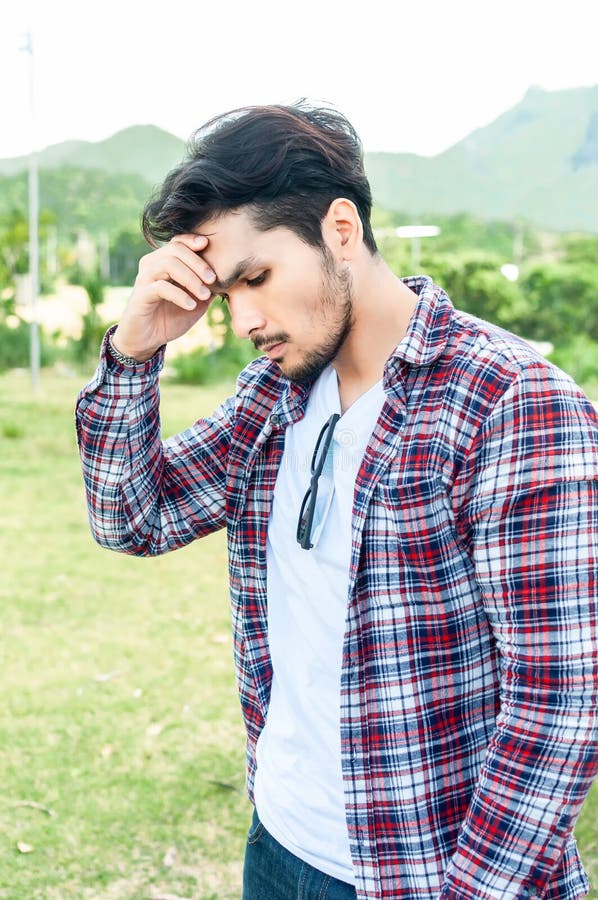 Young asian man feeling serious face is looking away while standing outdoors alone on nature autumn day .Man with bearded hipster stock image Young asian man feeling serious face is looking away while standing outdoors alone on nature autumn day .Man with bearded hipster stock image